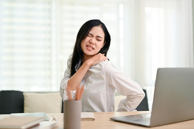 Asian businesswoman suffering from shoulders and back pain overworked office syndrome