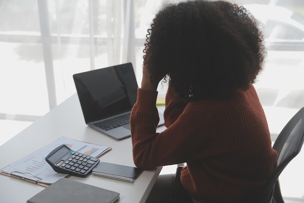 Asian Businesswoman Using laptop computer and working at office with calculator document on desk doing planning analyzing the financial report business plan investment finance analysis concept