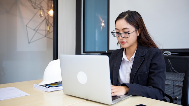 Asian businesswoman using laptop for work and doing internet research in her office