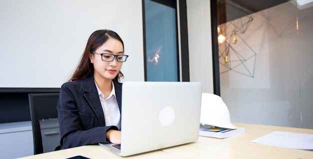 Asian businesswoman using laptop for work and doing internet research in her office