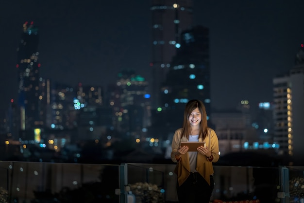 Asian businesswoman using tablet with smile action in the financial district area