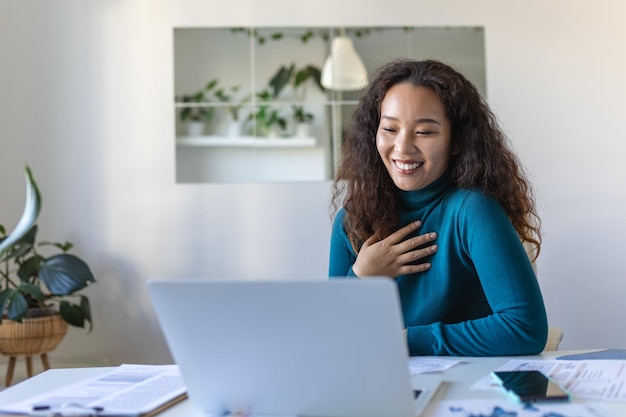 Asian businesswoman on a video call while sitting at her desk Shot of an attractive young woman using her laptop to make a video call at home