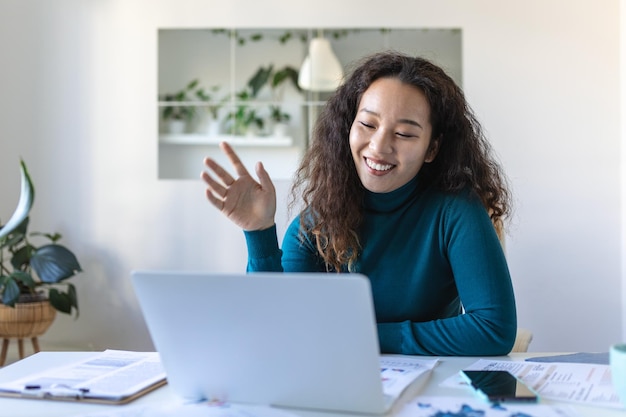 Asian businesswoman on a video call while sitting at her deskCropped shot of an attractive young woman using her laptop to make a video call at home