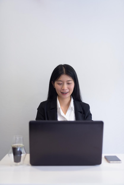 Asian businesswoman with laptop working in office coffee and notebooks on desk Professional setting