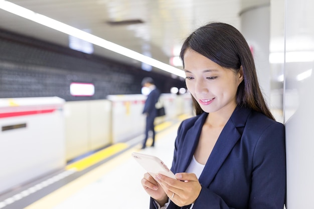 Asian businesswoman working on cellphone in train station