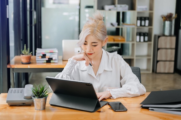 Asian businesswoman working in the office with working notepad tablet and laptop documents xA