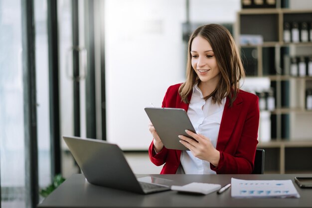 Asian businesswoman working in the office with working notepad tablet and laptop documents xA