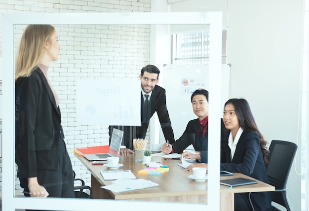 Asian and caucasian business man and woman look at caucasian manager woman giving presentation at work place.