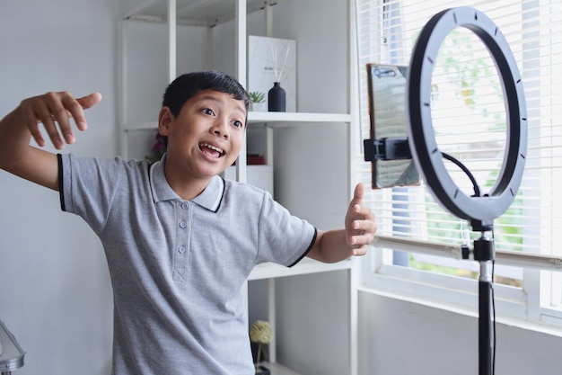 Asian child blogger recording dance video on digital smartphone. Online influencer boy social media