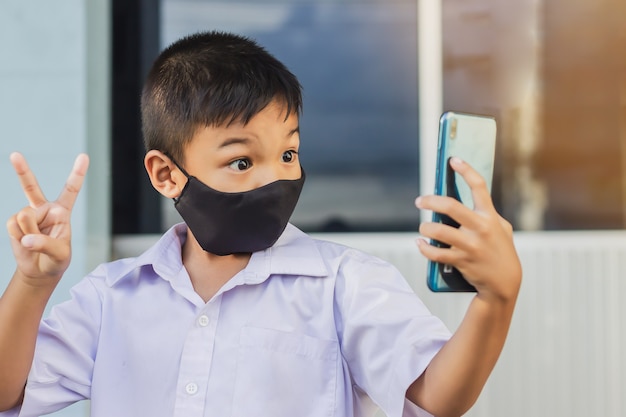 Asian child boy wearing black fabric mask on his face for prevent Covid-19 disease and corona virus.