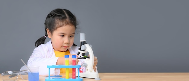 Asian child girl learning science chemistry with test tube making experiment at school laboratory. education, science, chemistry and children concept . Early development of children.