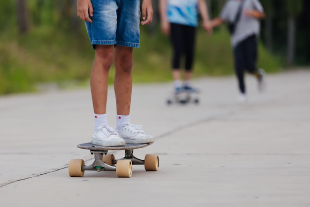 Asian child girl learning to skateboard outdoors. Kid having fun and playing skateboard on the road at the day time. Kid activity and extreme sport concept.