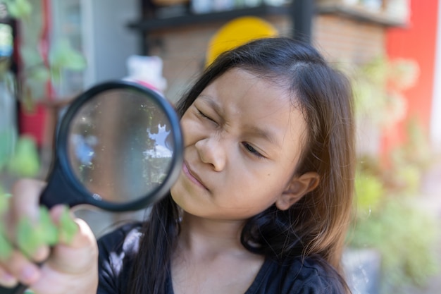  asian child girl looking through a magnifying glass 