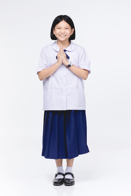 Asian child girl in student's uniform, acting sawaddee mean Hello .