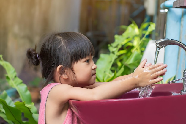 Asian child girl washing his hands before eating food and after play the toys at the washing bowl