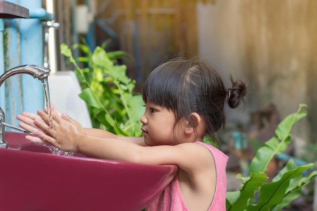 Asian child girl washing his hands before eating food and after play the toys at the washing bowl