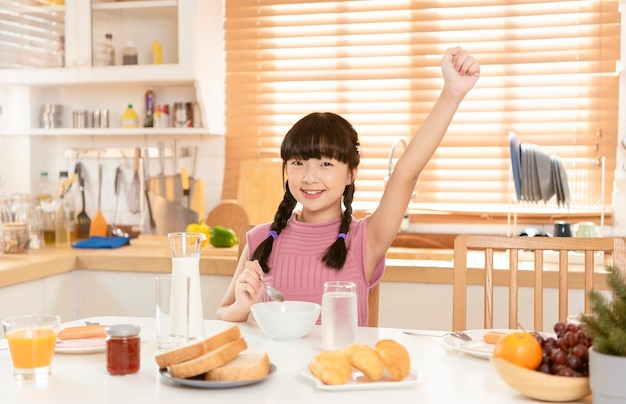 Asian child happy eating breakfast in kitchen room at home.