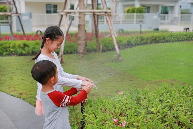 Asian children having fun to play water of watering the plants