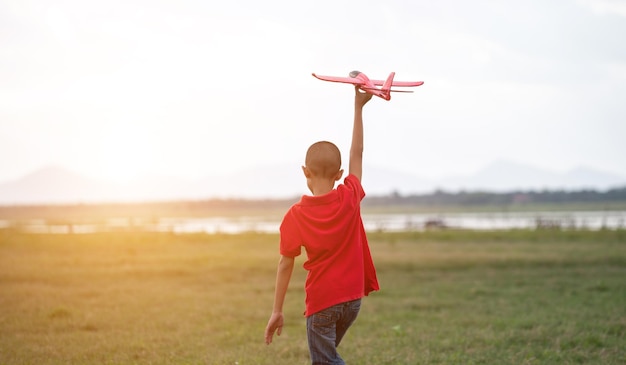 Asian children playing cardboard airplane together in the park outdoors