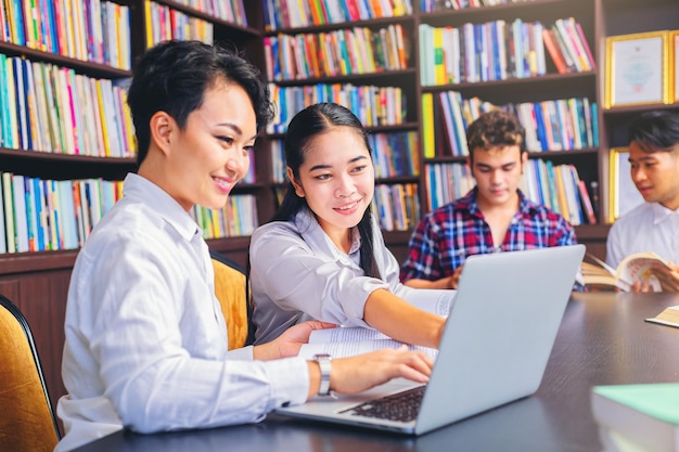 Asian college students sitting reading studying examining Tutor books with friends