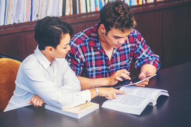 Asian college students sitting reading studying examining Tutor books with friends