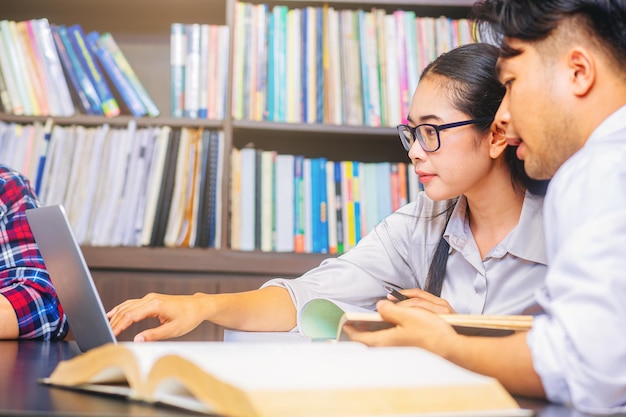 Asian college students sitting reading studying examining Tutor books with friends