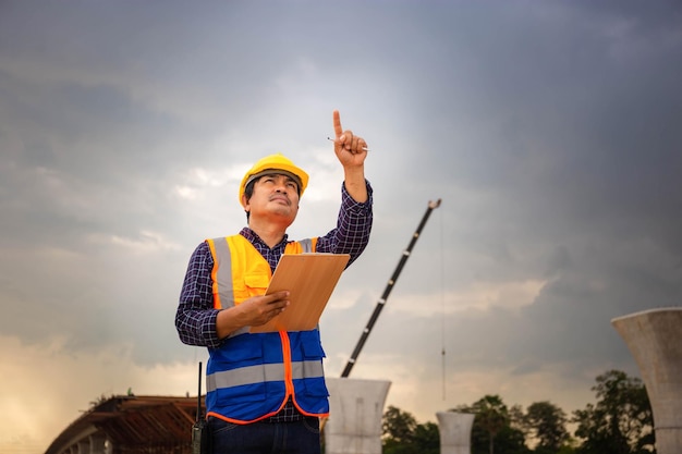 Asian construction engineer checking project at the building site Foreman worker in hardhat at the infrastructure construction site