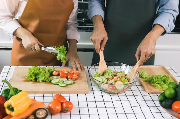 Asian couple enjoying cooking vegetable salad in the kitchen