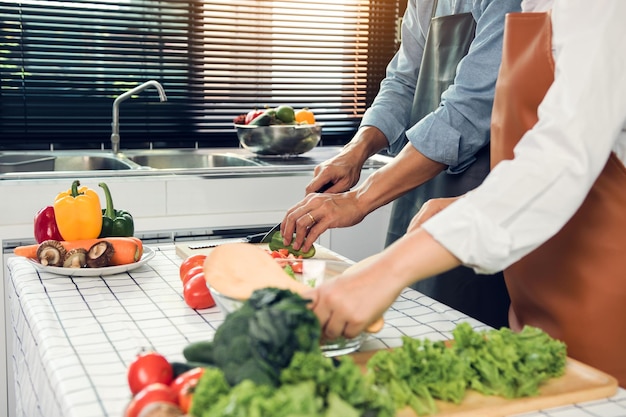 Asian Couple having fun while cooking a meal in kitchen