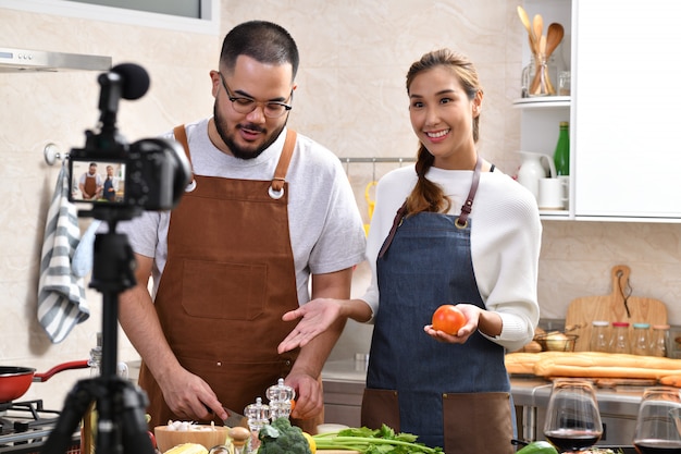 Asian couple recording a video in the kitchen