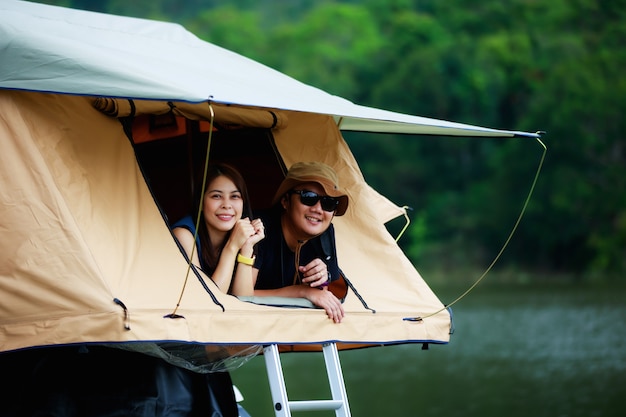 Asian couple relaxing in rooftop tent near the river