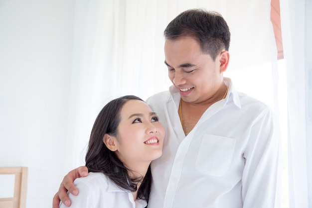 Asian couple smiling in bedroom