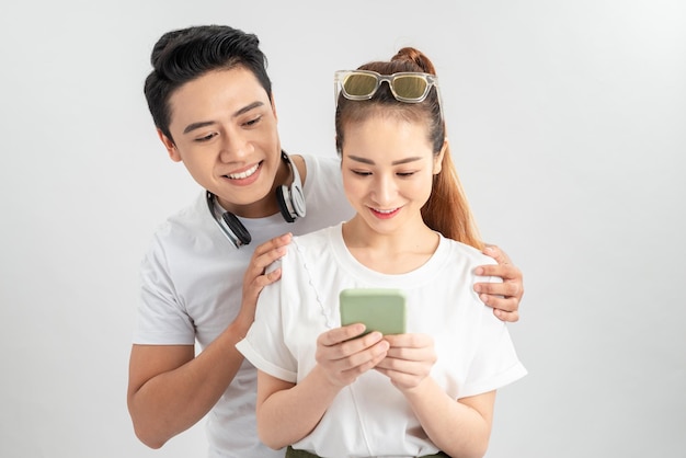 Asian couple using smartphone mobile handset standing isolated over white background