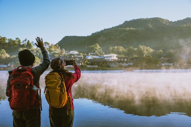 An Asian couple who is standing and watching the fog rising on the lake