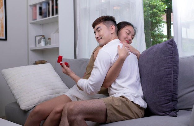 Asian couples are engaged and hugging affection on the sofa in the living room Man and Woman couple love moments happiness concept