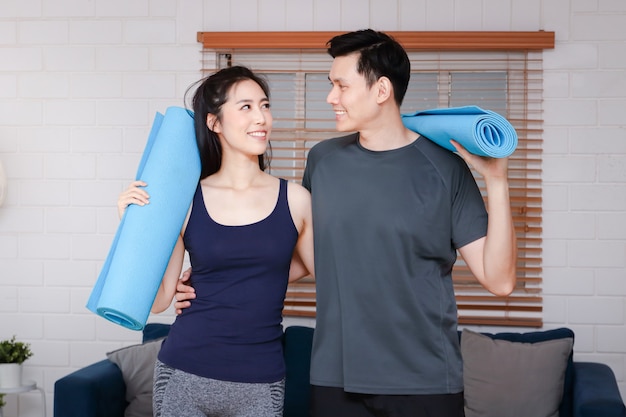 Asian couples exercise together at home in the living room. To maintain good health And social distance During COVID 19