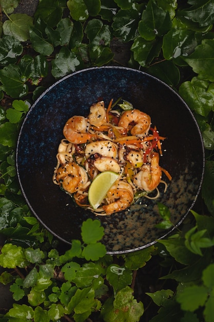 Asian cuisine. Shrimps with curry noodles. Appetizing dish on a background of leaves and plants