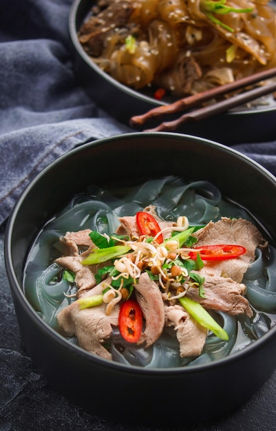 Asian cuisine, Vietnamese pho bo soup in a black plate on a dark