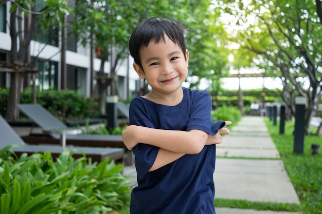 Asian cute boy smile and looking at green nature garden.