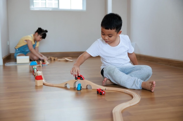 Asian cute girl playing wood block building rail way and road on the floor at home