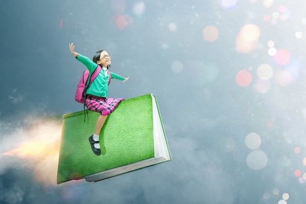 Asian cute girl with glasses and backpack sitting on the book