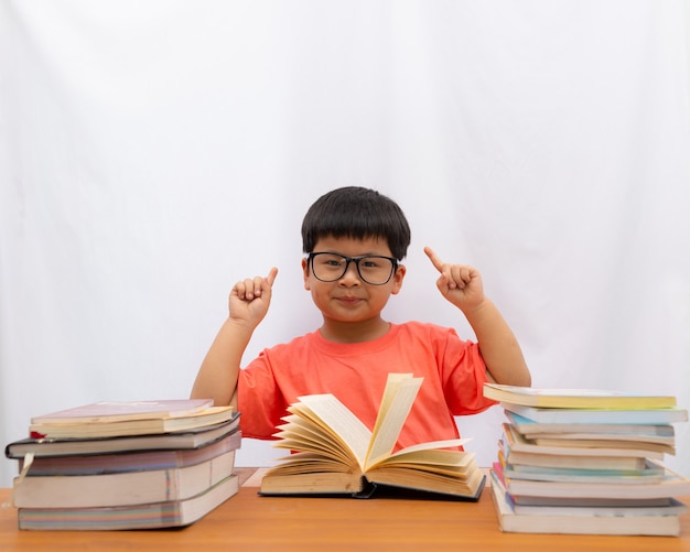 Asian cute a little boy reading with finger holding on white background,