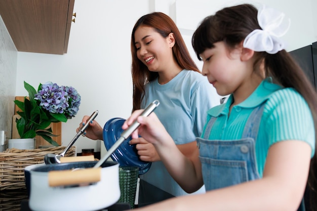 Asian cute mom teach daughter cooking food in kitchen at home for family day Funny and smiling toget