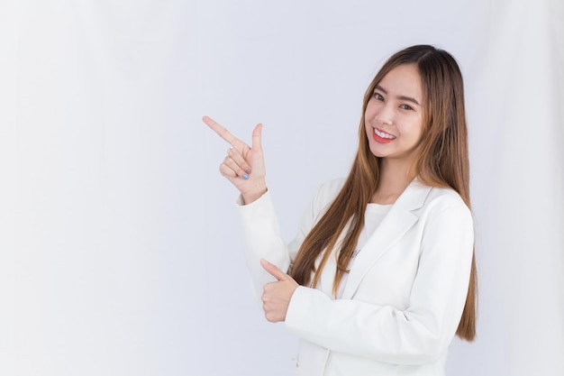 Asian cute woman in white suit acts exciting and point up to present something on white background