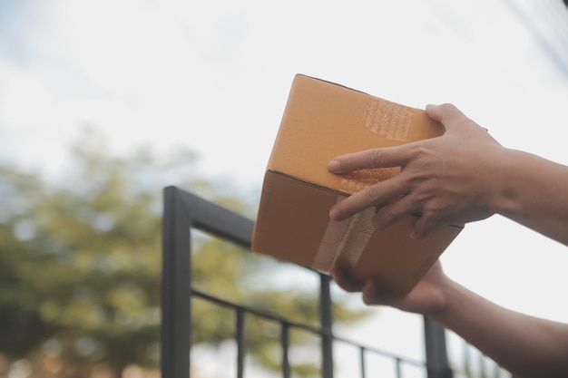 Photo asian delivery express courier young man use giving boxes to woman customer he wearing protective face mask at front home