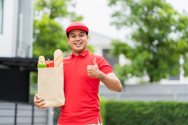 Asian Delivery man holding the paper bag with food