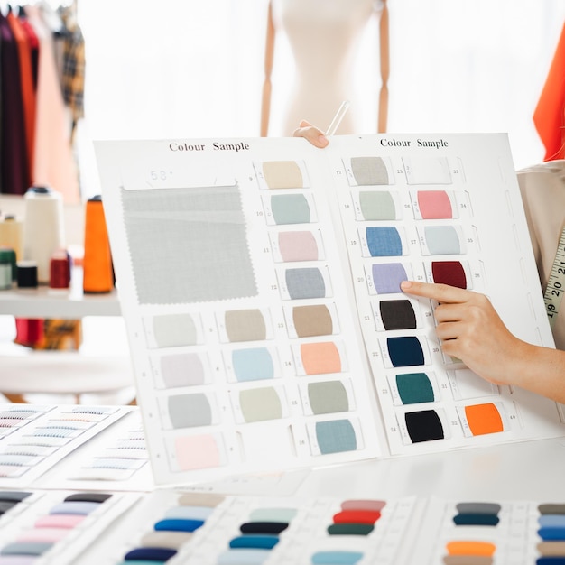 Asian designer woman discussing new paint colors comparing shades on a set of color in a shop