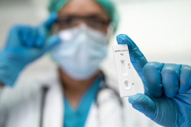 Asian doctor holding Saliva Antigen Test Kit for check Covid19 coronavirus in hospital