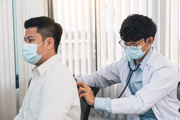 Asian doctor is using a stethoscope listen to the heartbeat of the patient