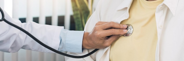 Asian doctor is using a stethoscope listen to the heartbeat of the patient